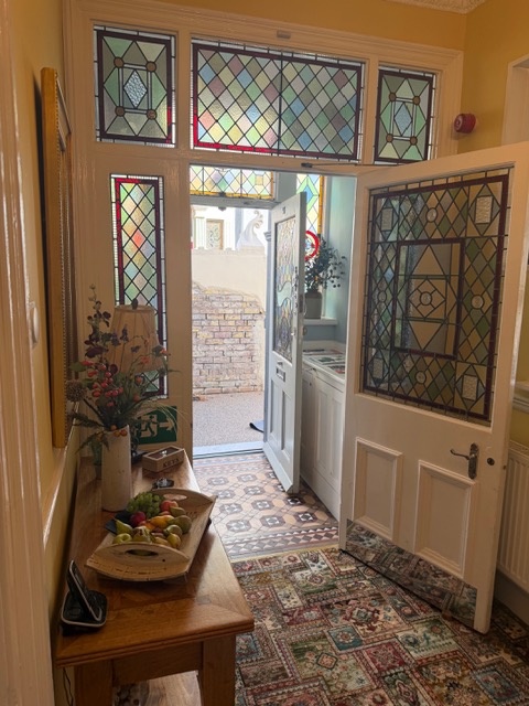 The main entrance hallway with stained glass and a console table