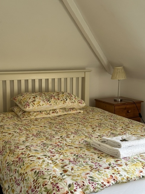 A Standard double room with a sloped ceiling and made-up bed